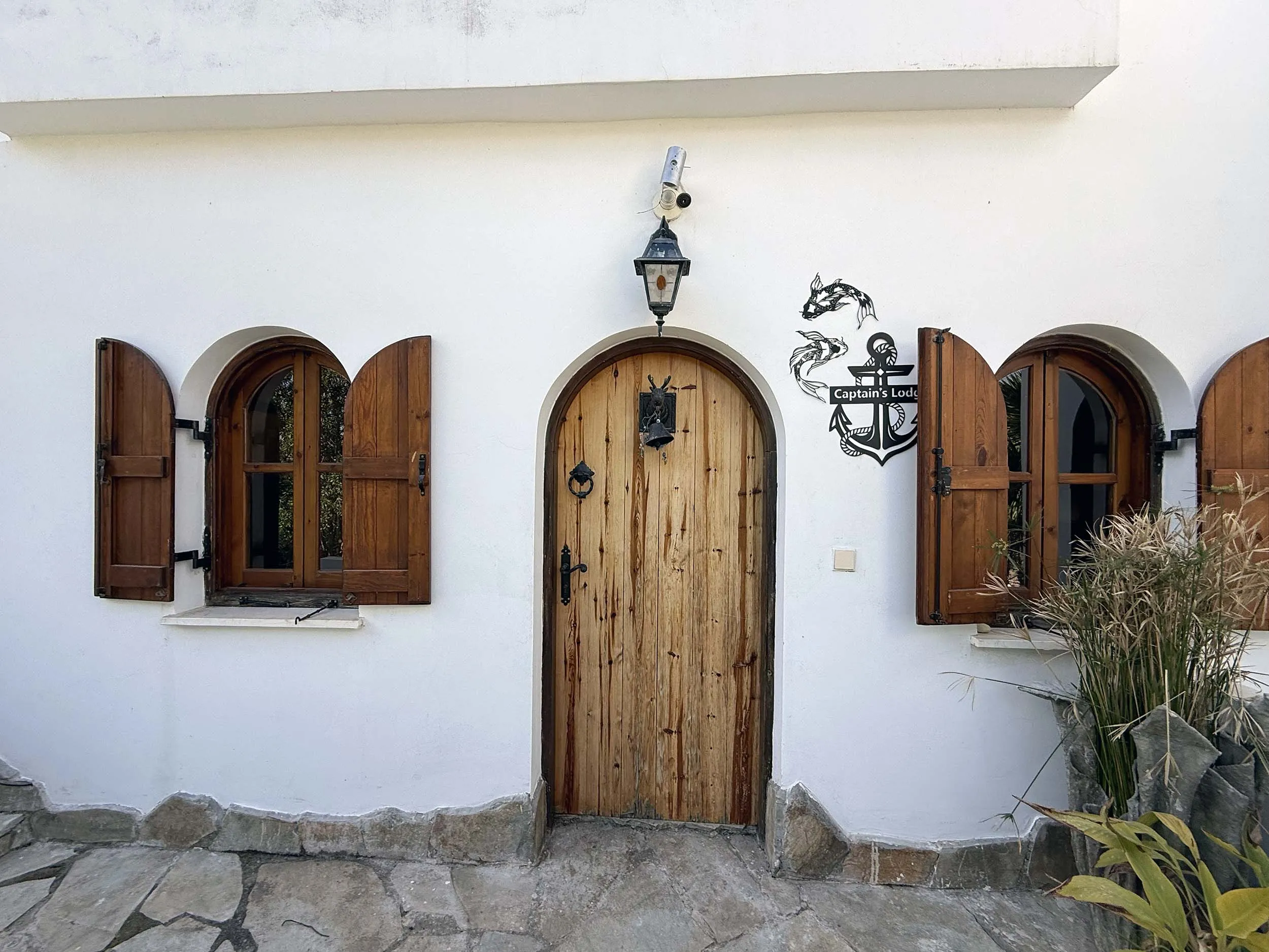 Rustic wooden arched door with Captain's Lodge anchor sign and traditional shuttered windows