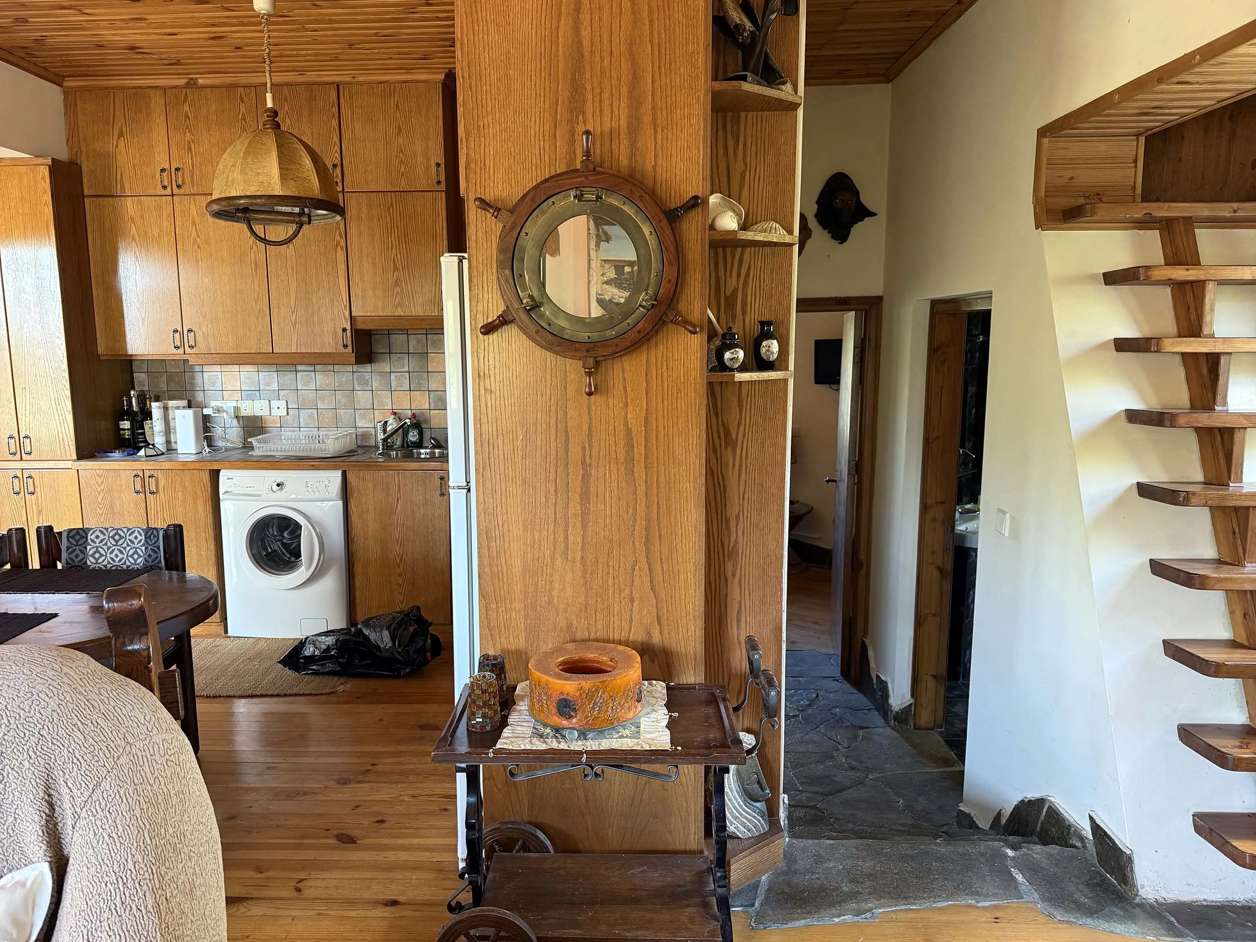 Cottage kitchen and open-plan interior with ship's wheel decor and wooden staircase