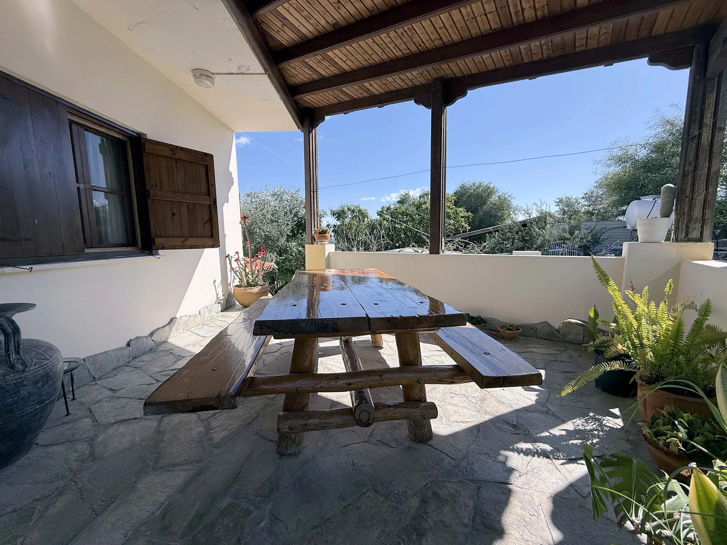 Shaded stone terrace with rustic wooden picnic table and garden views